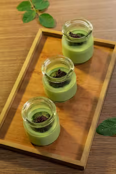 three avocado desserts in a cup on top of a tray.